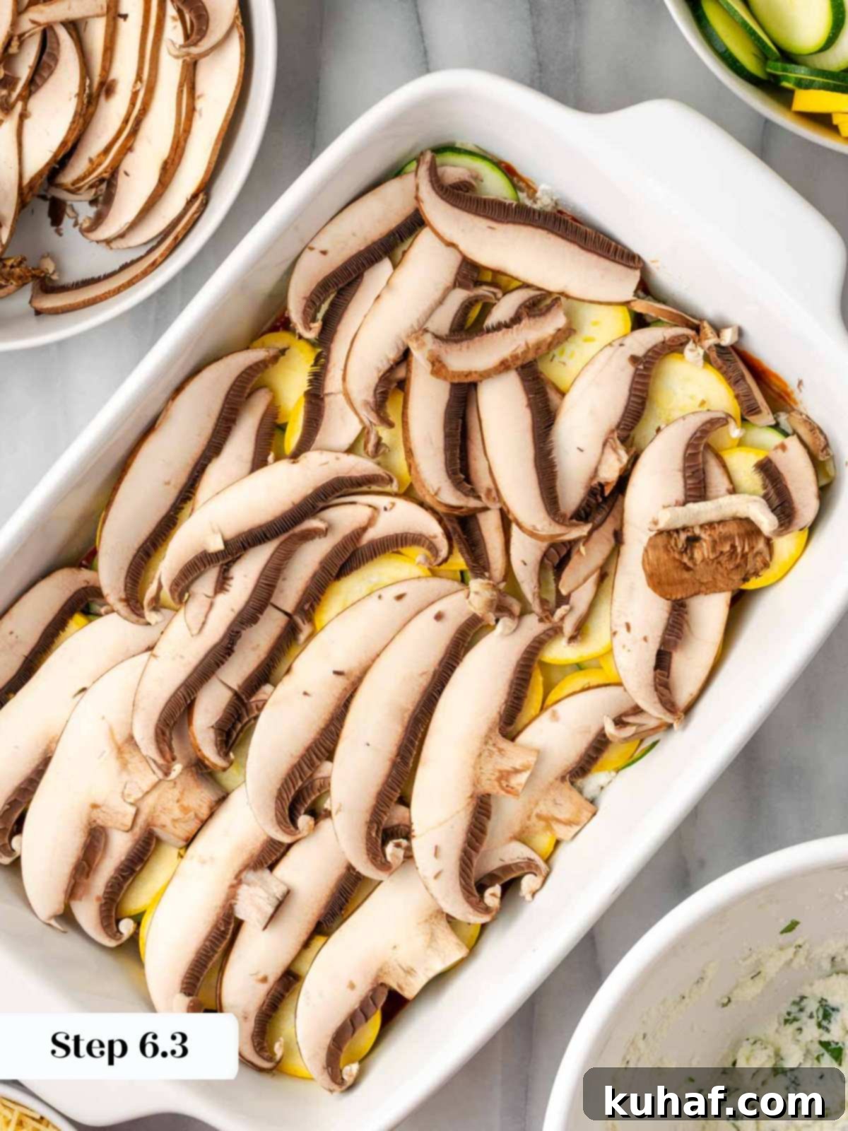 Sliced portobello mushrooms being added as a layer on top of the squash in the lasagna dish.