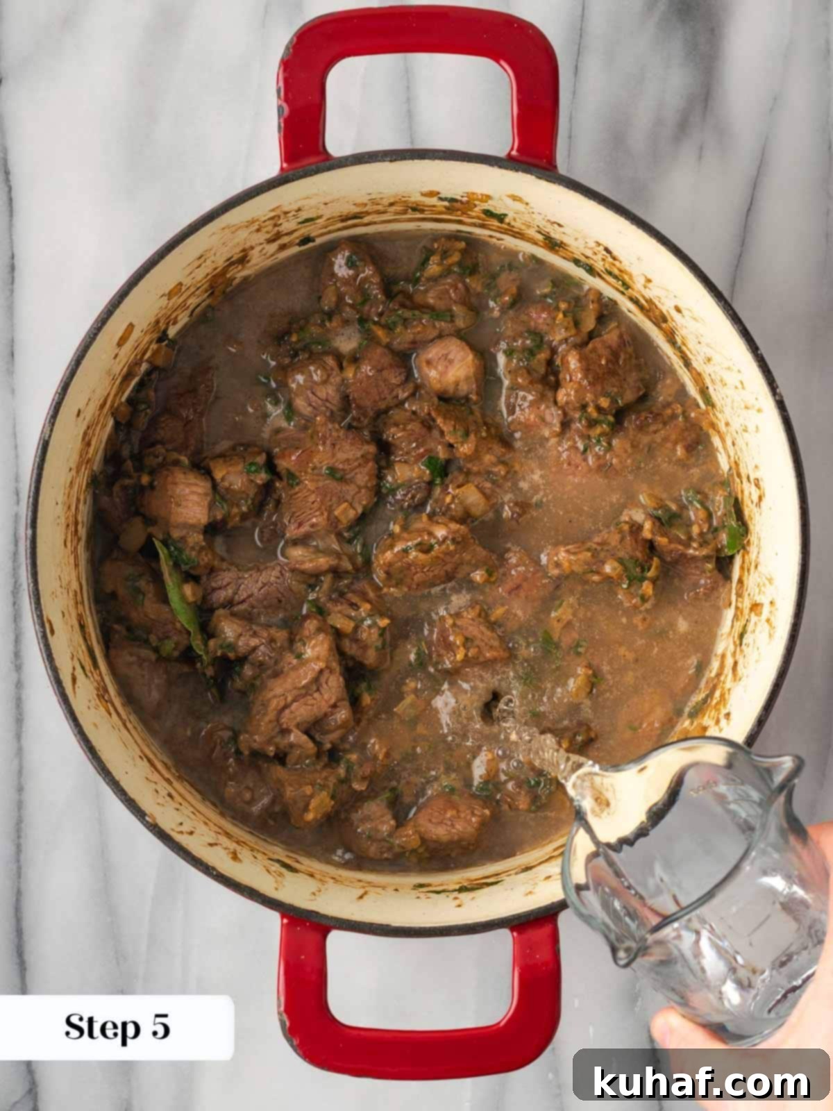 Adding water to beef stew cooking in a Dutch oven with vegetables.