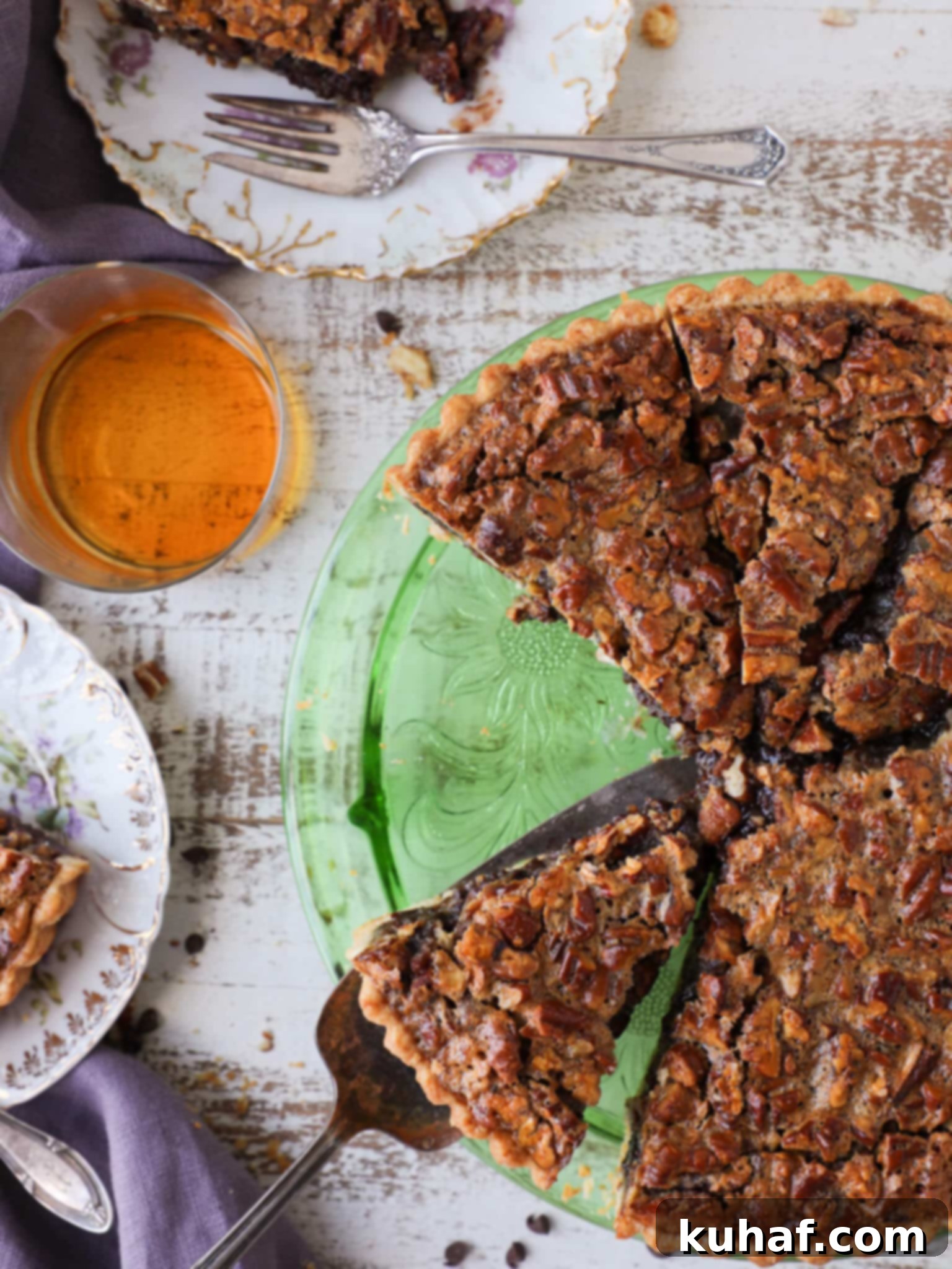 A slice of Bourbon Chocolate Pecan Tart being served on a white plate, highlighting its rich layers and flaky crust.
