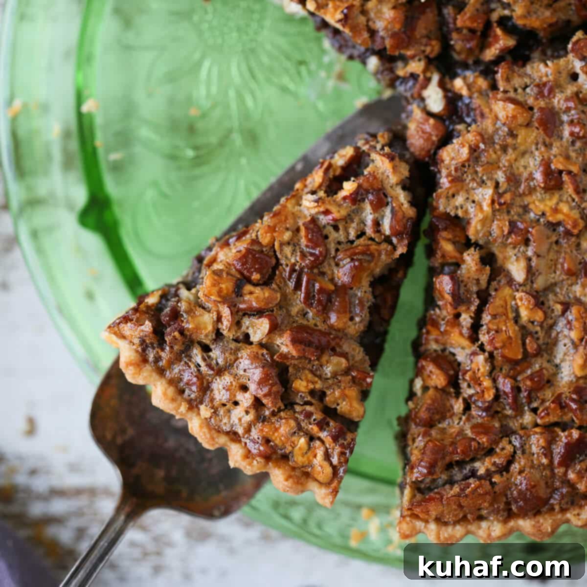 A tempting slice of Bourbon Chocolate Pecan Tart served on a vintage green depression glass cake plate.