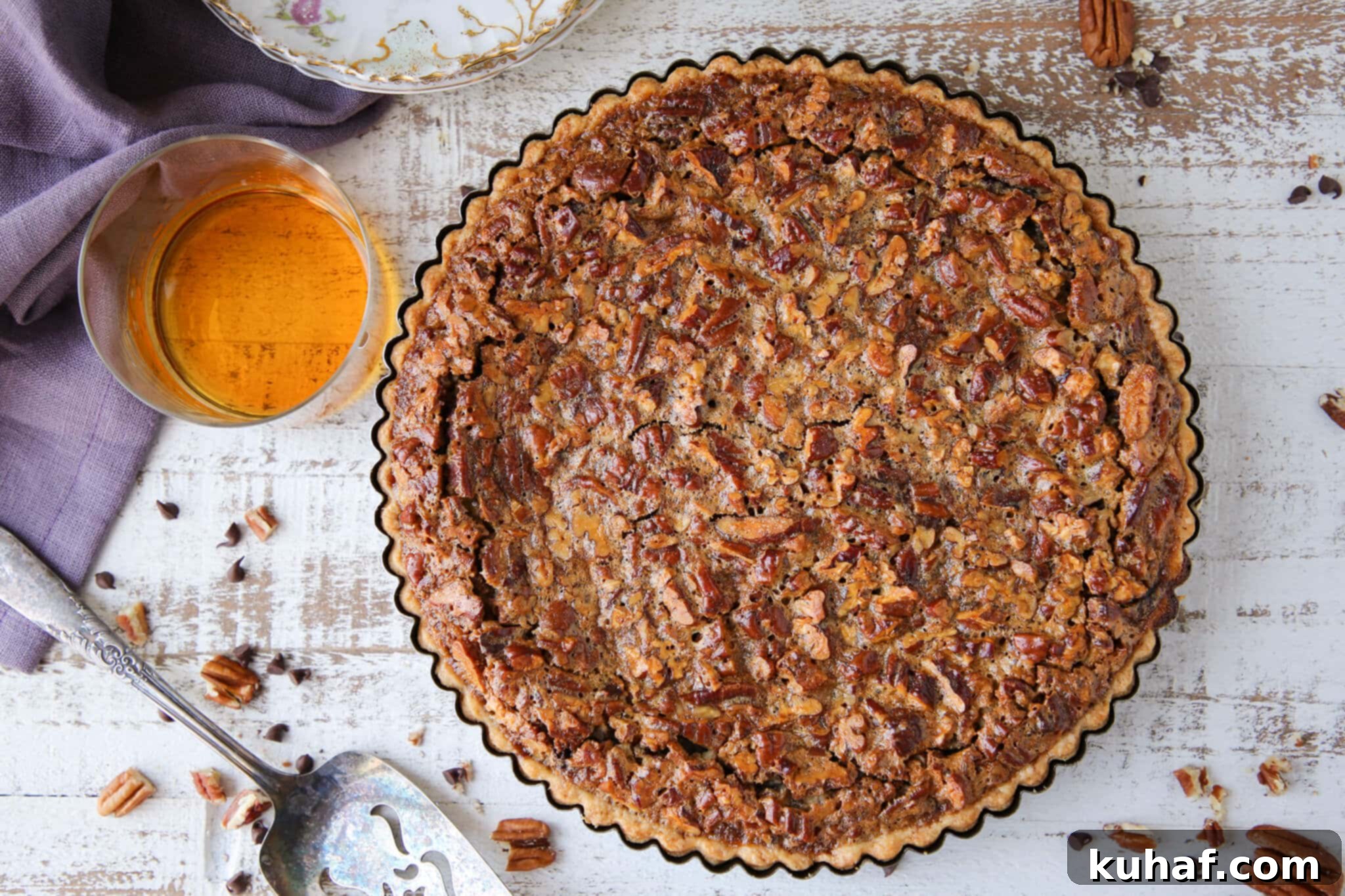 The Bourbon Chocolate Pecan Tart nestled in its tart pan, showcasing the golden crust and dark, rich filling before slicing.