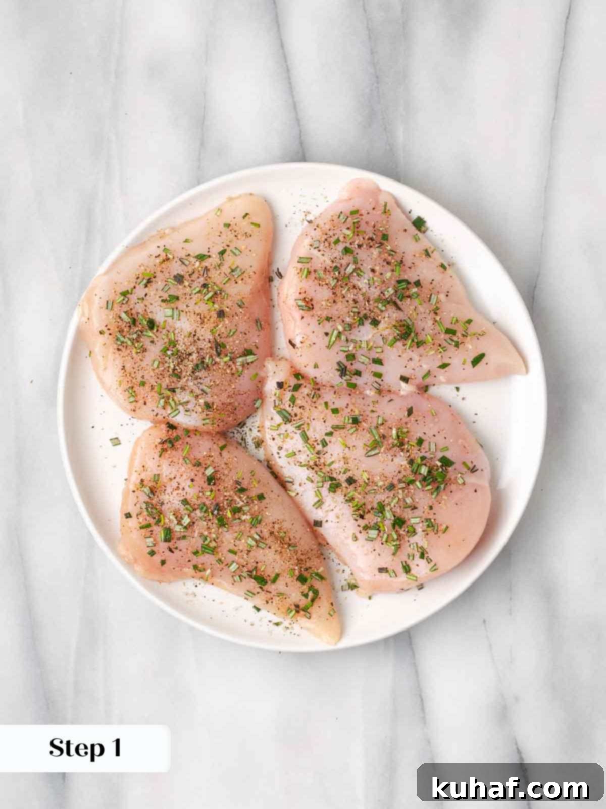 Sun-Kissed Marinara Chicken 5 seasoned raw chicken breasts on white plate.