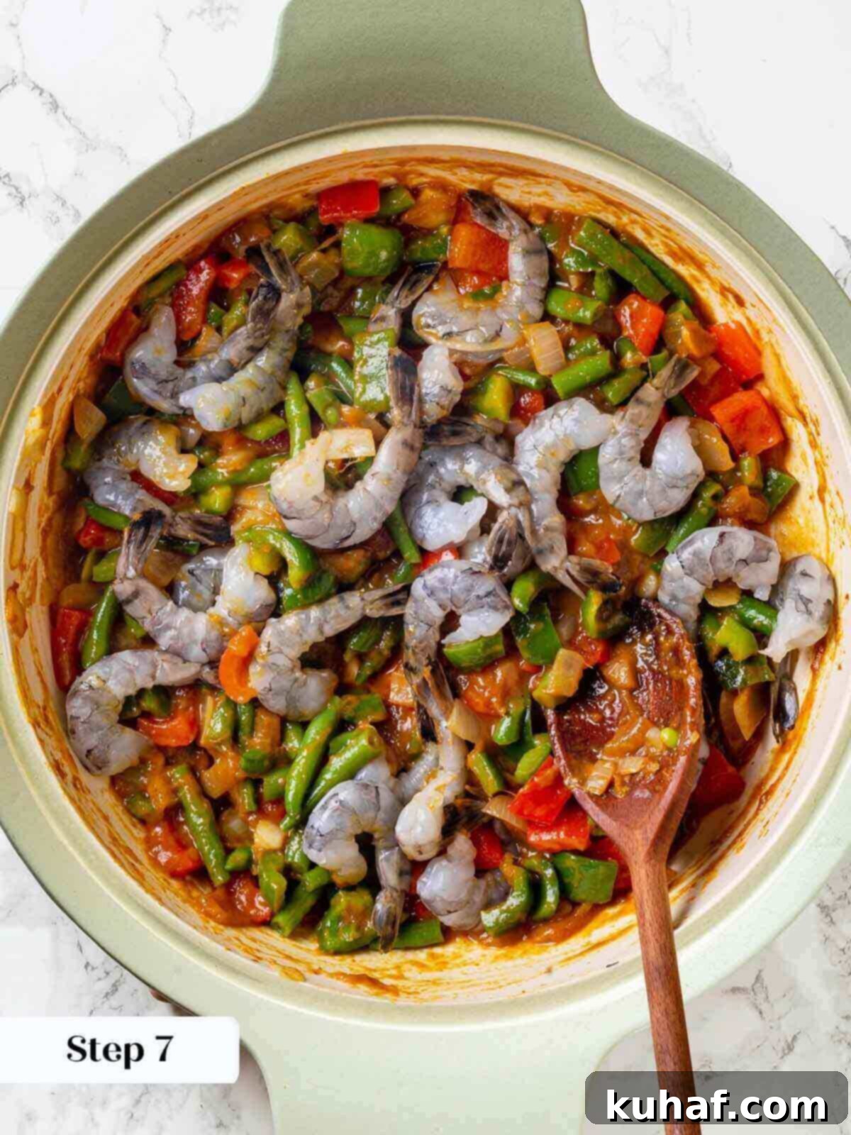 Adding fresh shrimp to the simmering curry mixture in a skillet.