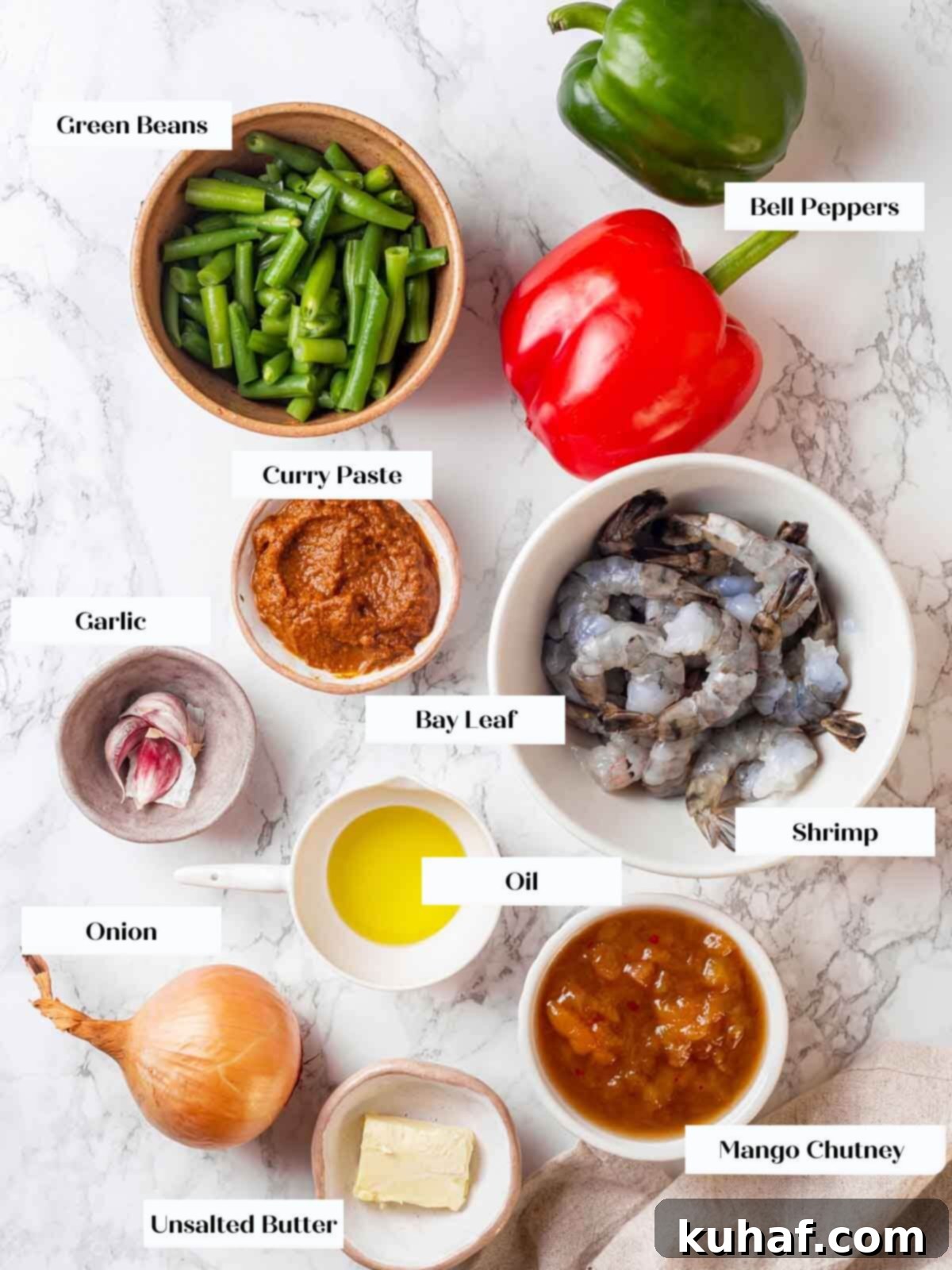 Curry ingredients: onions, bell peppers, green beans, garlic, curry paste, mango chutney, and butter laid out.