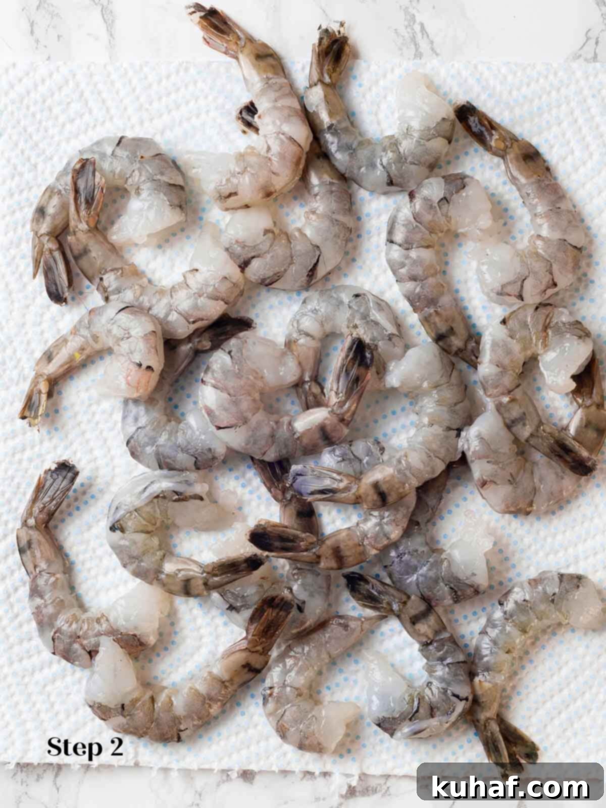 Raw shrimp being prepared, deveined, and patted dry before cooking for the curry.