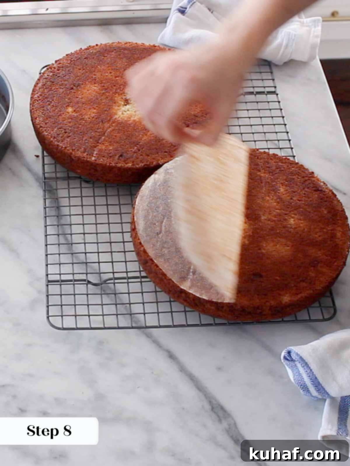 A baker carefully spreading the first layer of cream cheese buttercream onto a cake layer, ensuring an even coat.