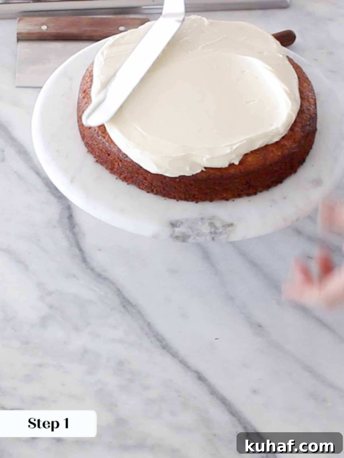 The second layer of cake being placed atop the first, ready for its generous layer of cream cheese buttercream.