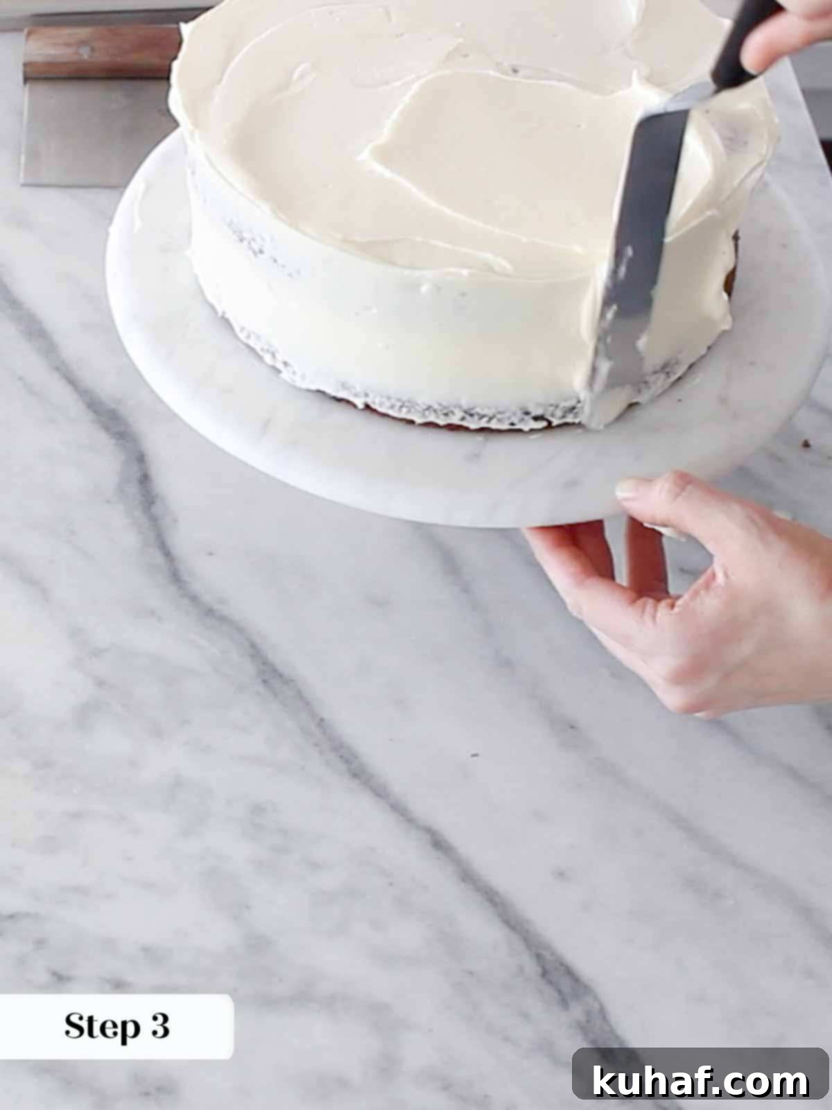 A smooth, thin crumb coat of cream cheese buttercream applied to the cake, ready for chilling before the final layer.