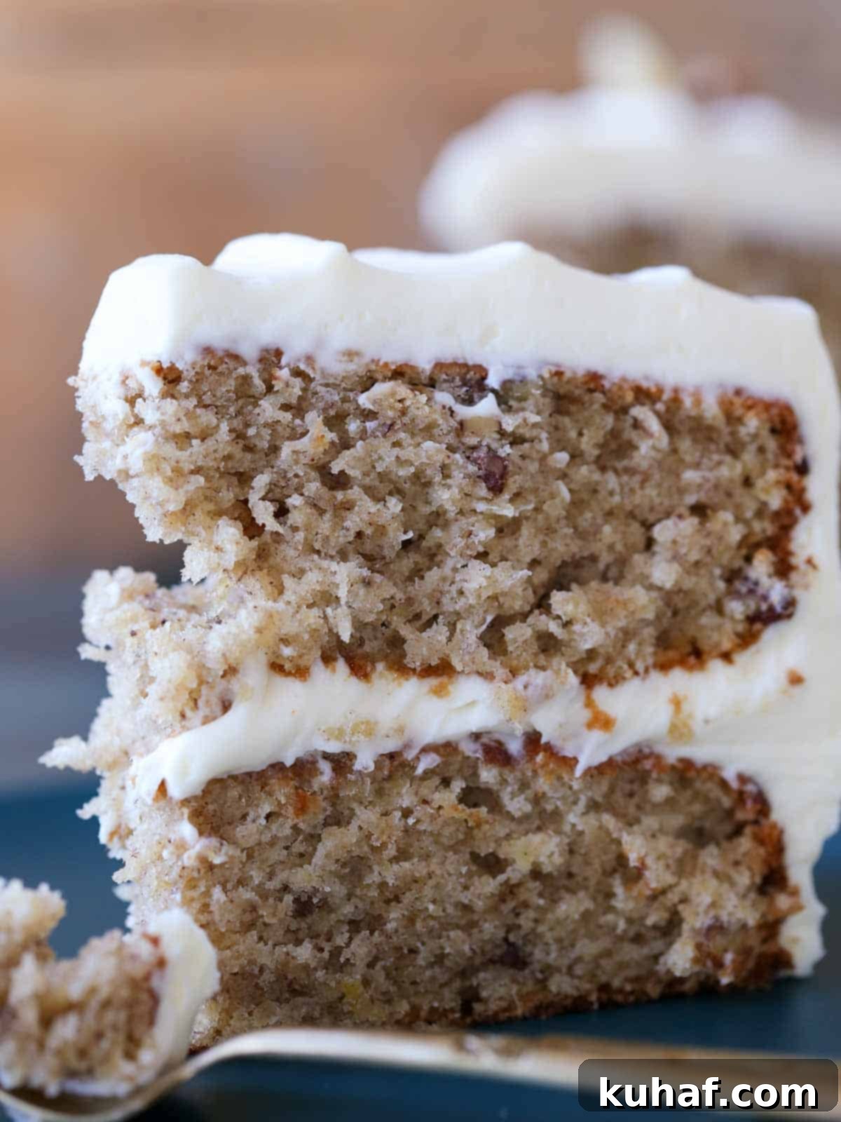A close-up shot of a moist and tender slice of hummingbird cake on a plate with a gold fork, highlighting its inviting texture.