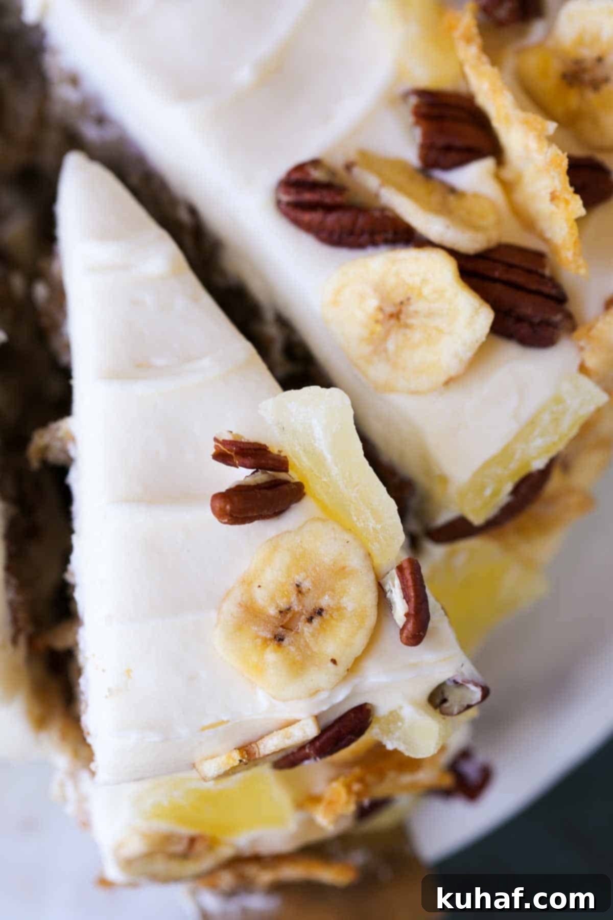 A beautifully decorated slice of hummingbird cake next to a whole unsliced cake, showcasing its elegant mosaic garnish.