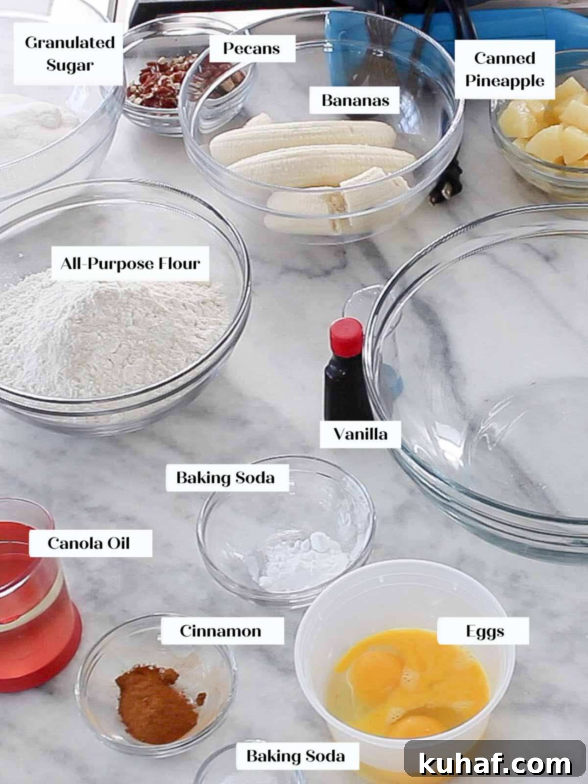 A selection of fresh and pantry ingredients laid out on marble, ready for making hummingbird cake.
