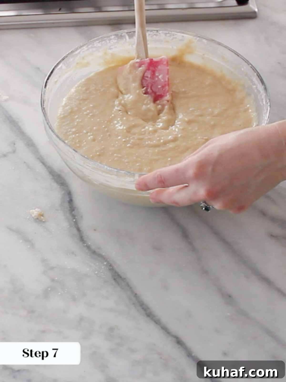 A spatula gently folding dry ingredients into the cake batter, ensuring no overmixing for a tender crumb.