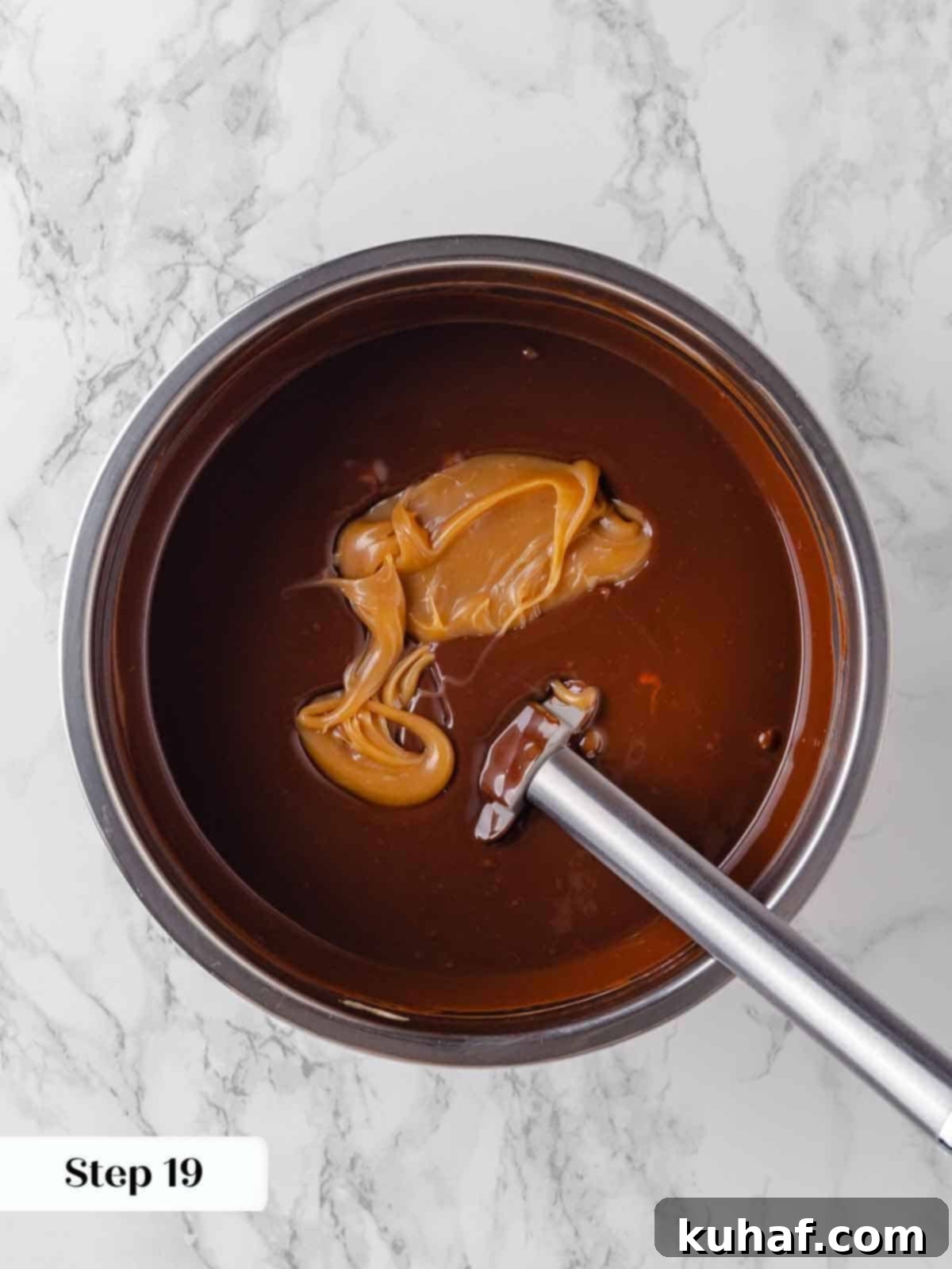 adding salted caramel sauce to hot ganache for frosting.