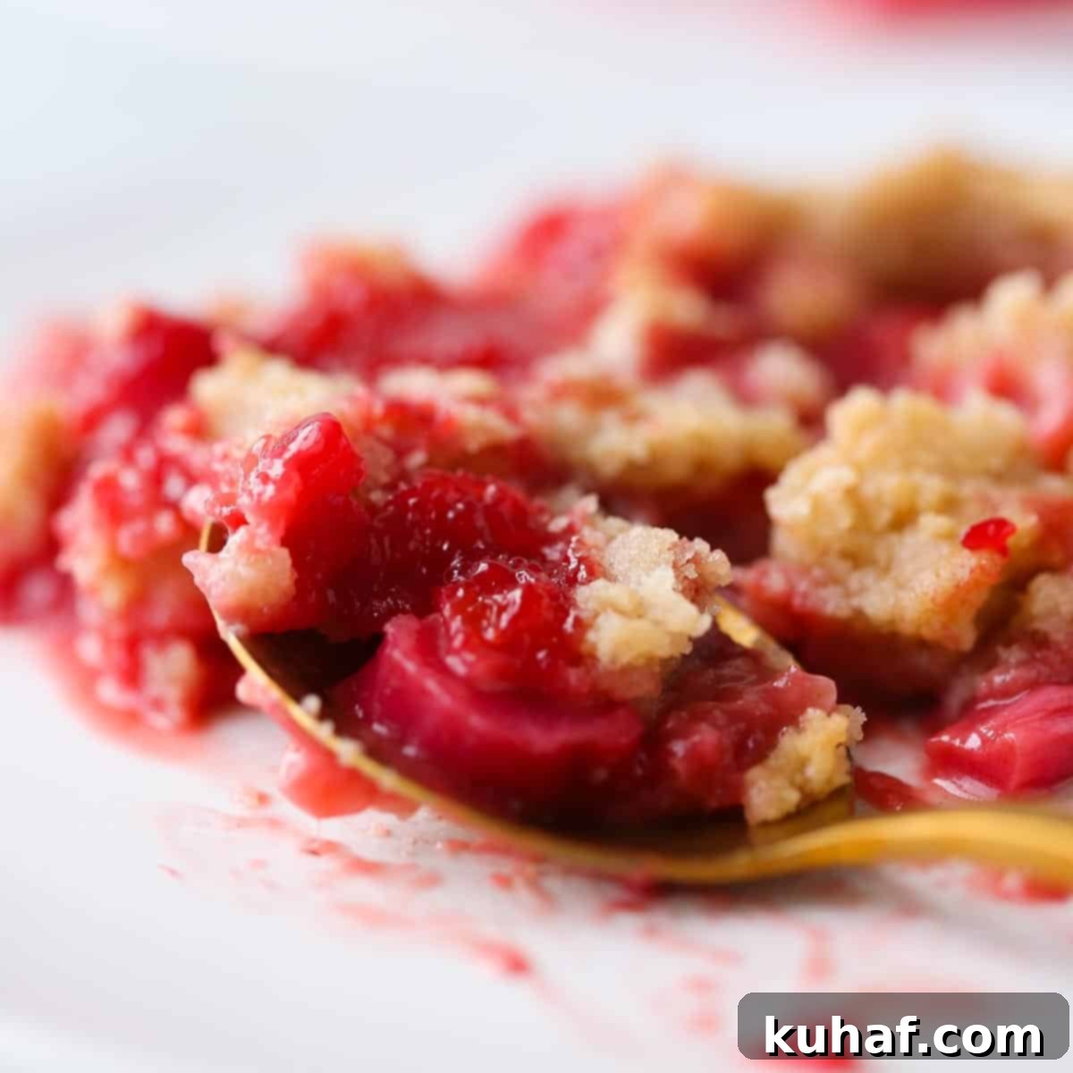 Close-up of juicy strawberries and rhubarb baked under golden crumble topping.