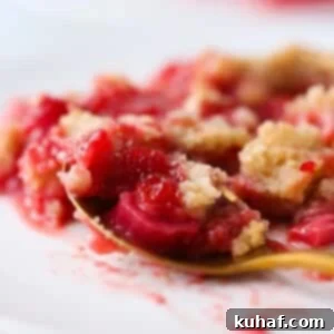 Close-up of juicy strawberries and rhubarb baked under golden crumble topping.