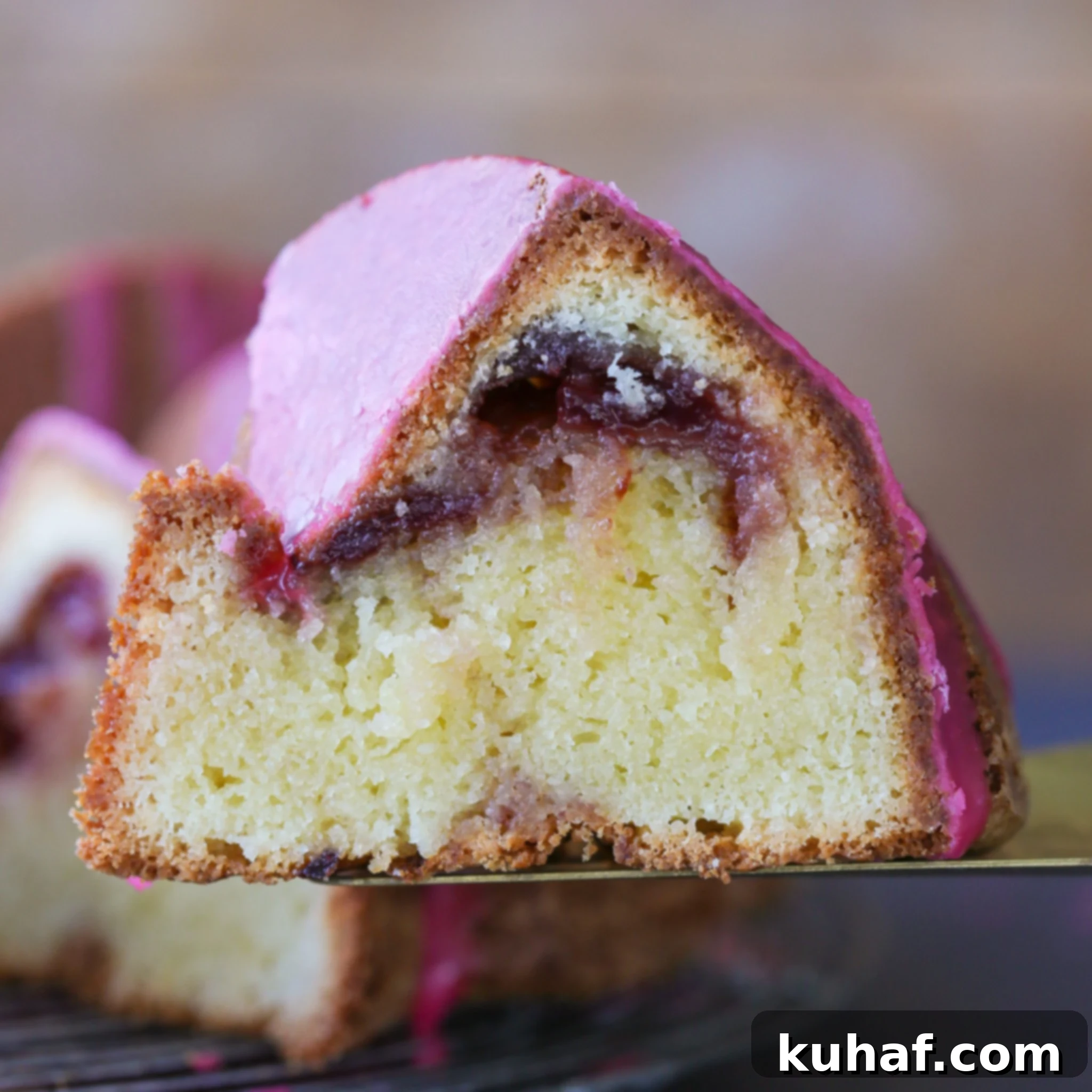 Slice of Cherry Almond Pound Cake with a visible cherry jam swirl and pink glaze