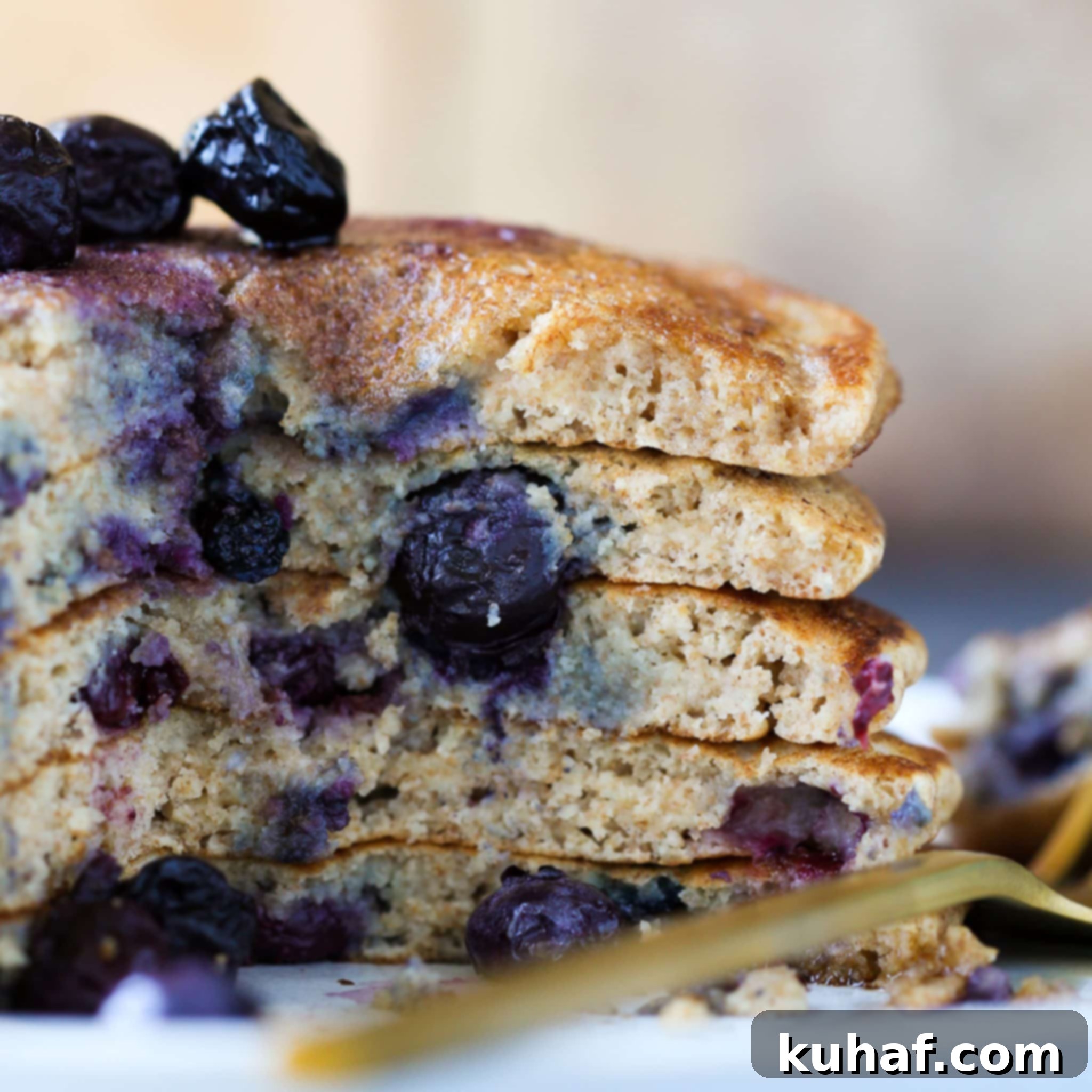 Whole Wheat Pancakes stacked high with fresh blueberries and a drizzle of maple syrup.