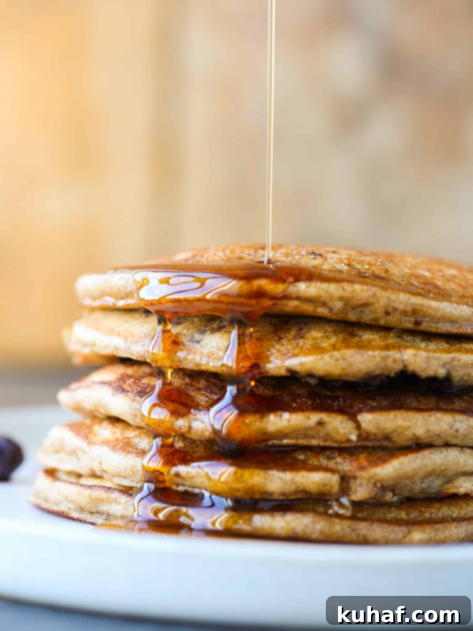 Close-up of a single whole wheat pancake on a griddle, bubbles forming as it cooks.