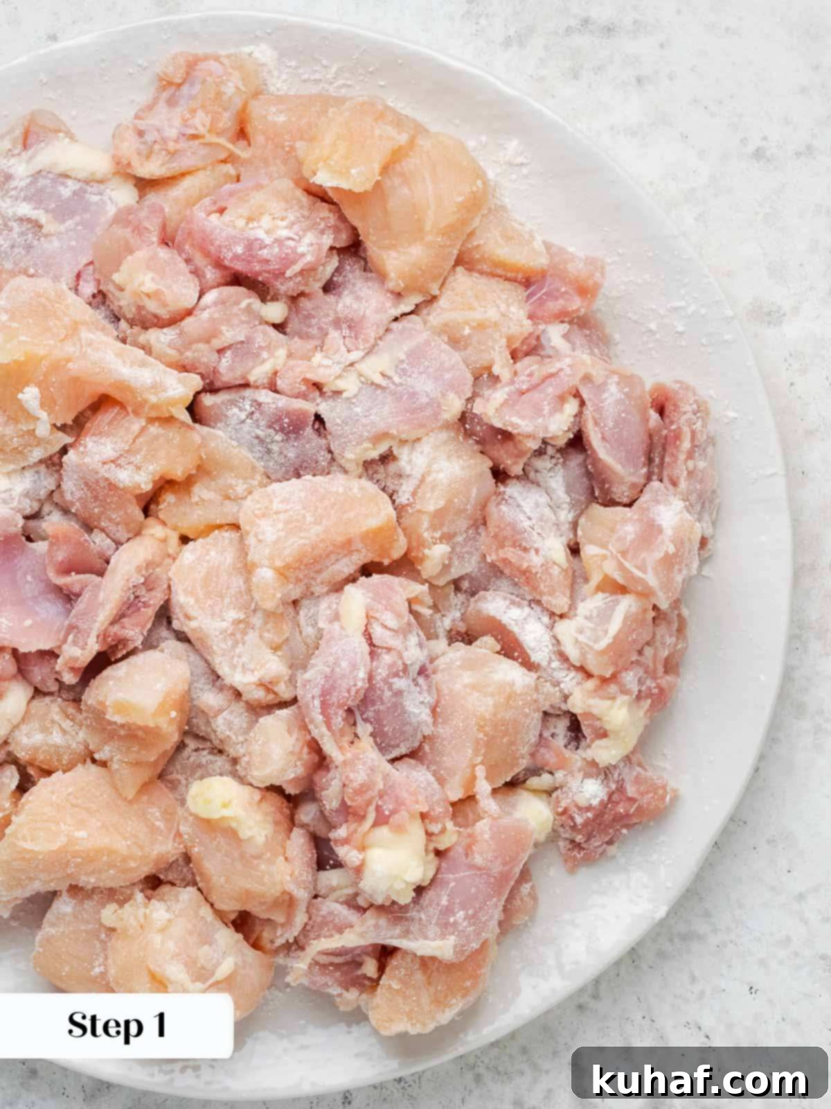Chicken pieces uniformly cut and lightly coated with flour, ready for cooking.