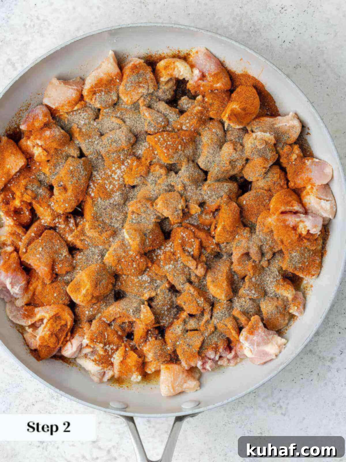 Chicken browning in a hot pan with paprika, salt, and pepper, developing a rich color.
