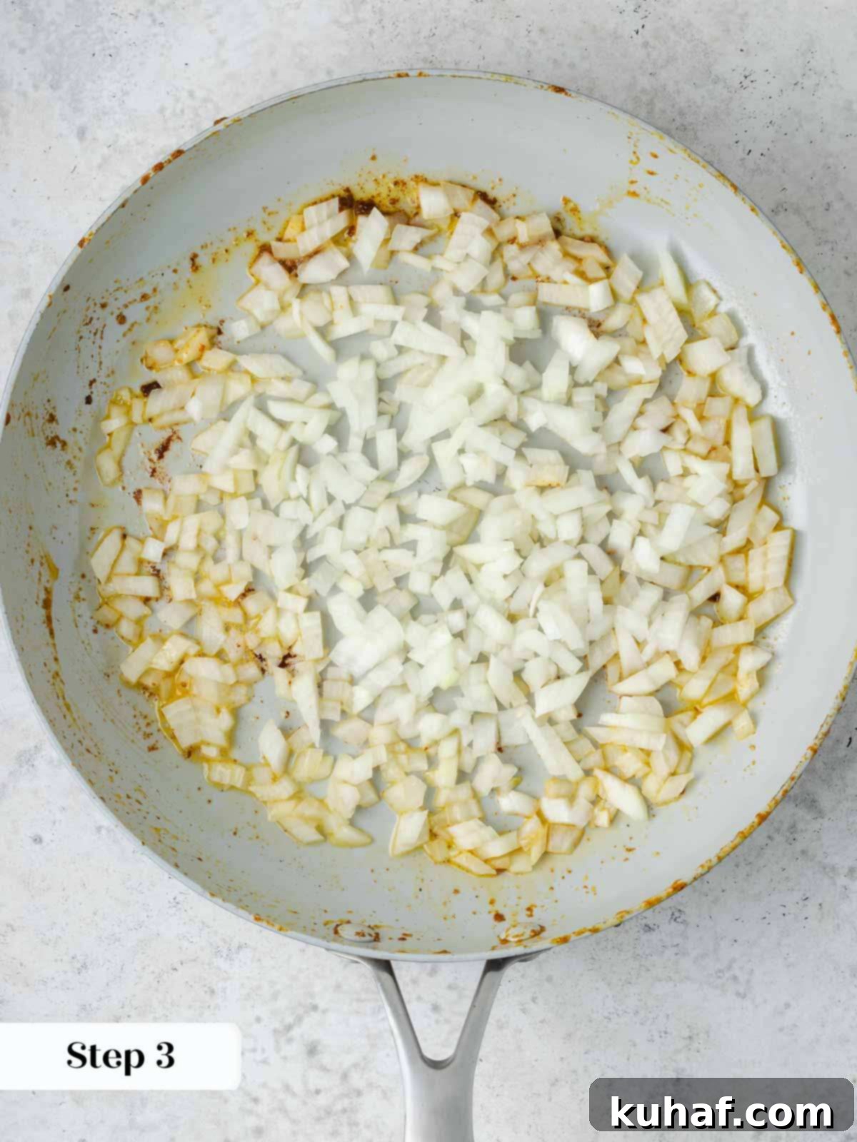 Finely chopped yellow onions sautéing in melted butter in a skillet, becoming translucent.