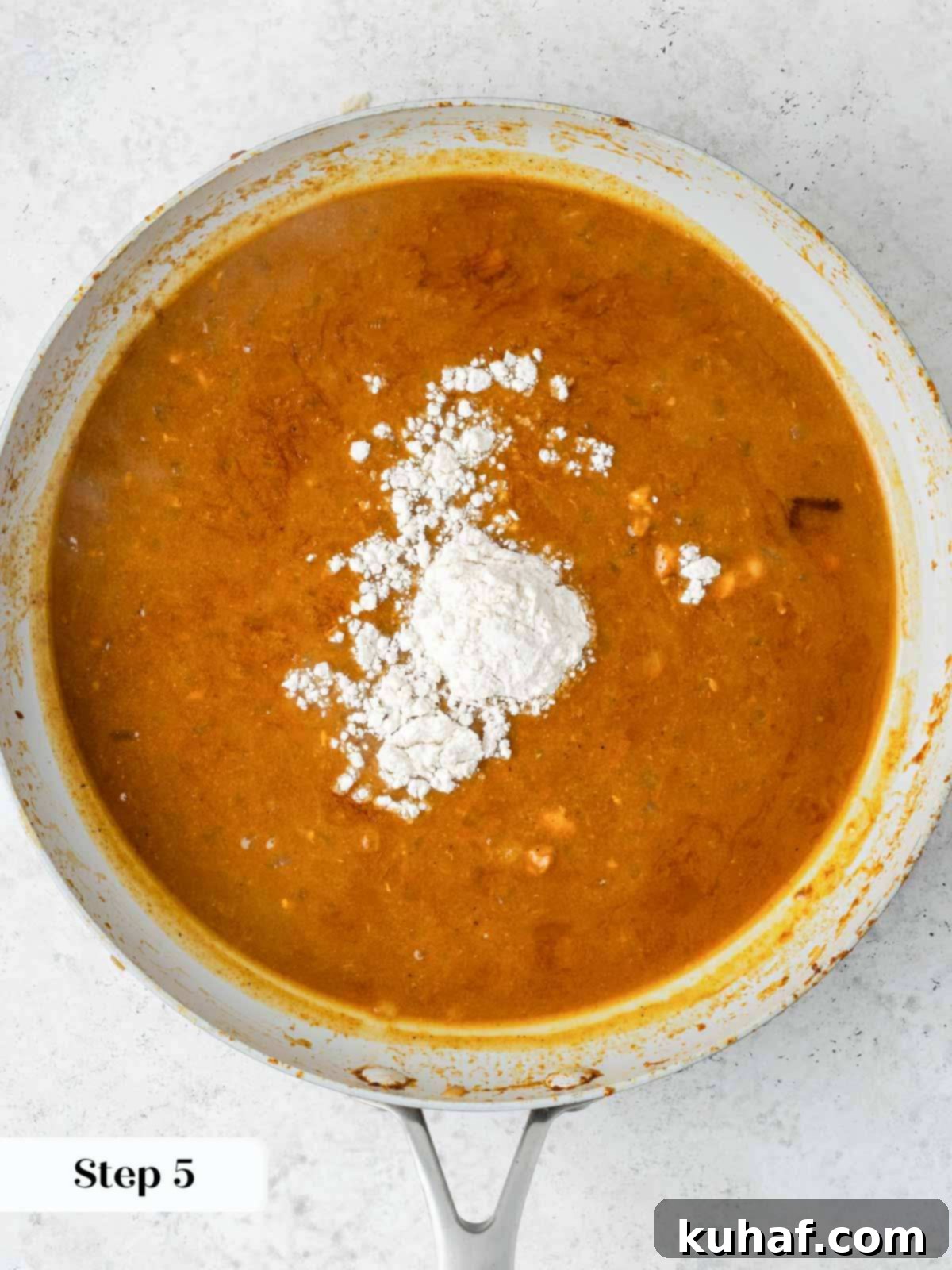 All-purpose flour being stirred into the simmering paprika sauce to thicken it to a perfect consistency.