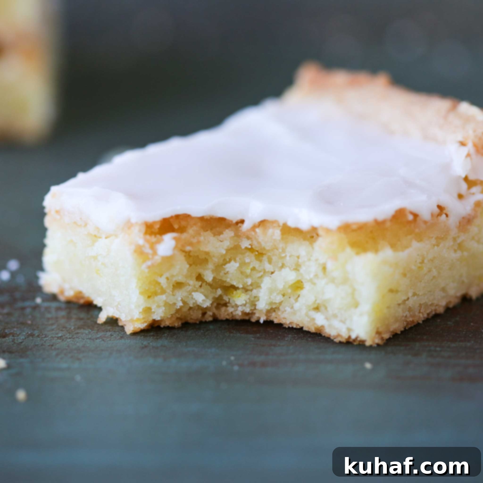 Close-up of a single Lemon Blondie slice, showing the moist, dense interior and a generous layer of lemon glaze.