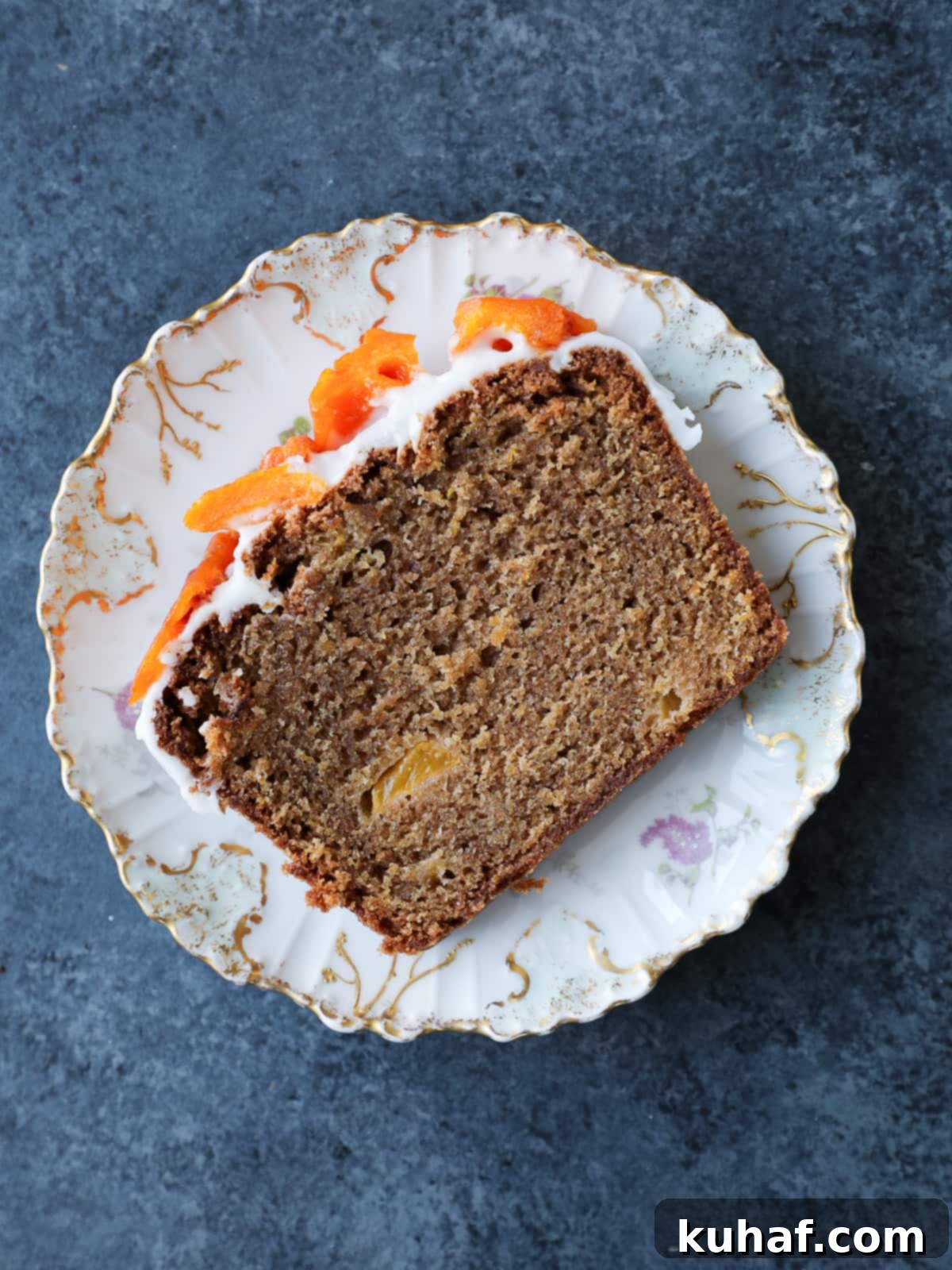 A single slice of moist peach cake on a white plate, showcasing its soft, golden crumb, visible peach pieces, and glistening almond glaze.