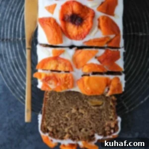 Beautifully glazed peach loaf cake, adorned with dried peach slices and slivered almonds from an overhead view.