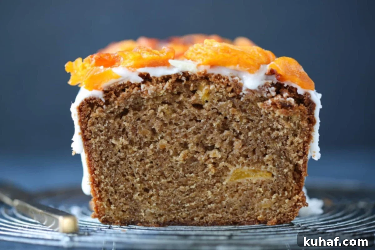Close-up of a perfectly sliced moist peach cake, revealing its incredibly soft, tender crumb and abundant, juicy peach pieces distributed throughout.