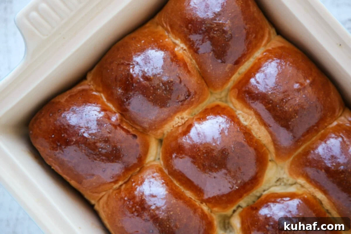 Two golden-brown easy dinner rolls on a white surface, showcasing their fluffy texture