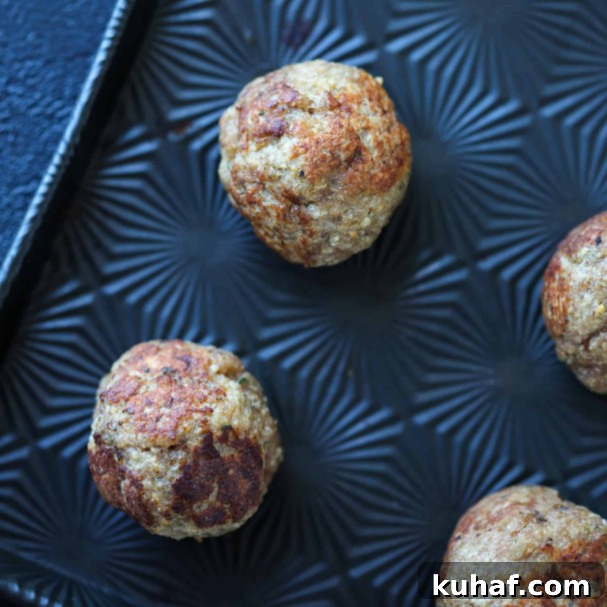 Baked turkey meatballs on a black sheet pan, perfectly browned.