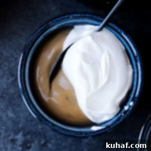 Caramel colored butterscotch pudding in a dark bowl with half of the cover topped with white whipped cream.