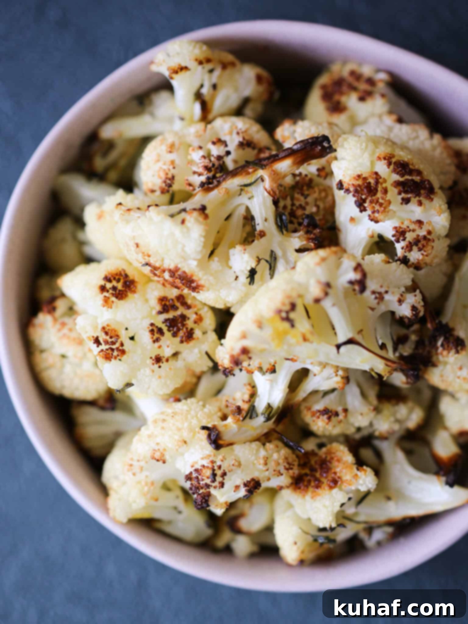 Easy Rosemary Lemon Roasted Cauliflower pink bowl on a green surface