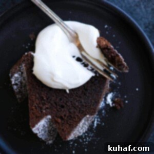 A slice of chocolate pound cake with whipped cream dolloped on top.