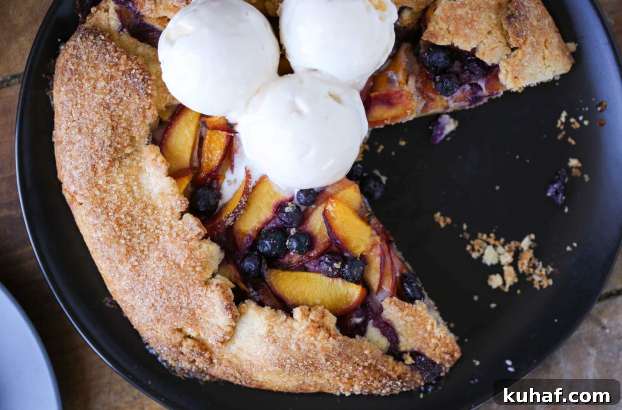 A slice of Nectarine Blueberry Galette topped with a scoop of vanilla ice cream.