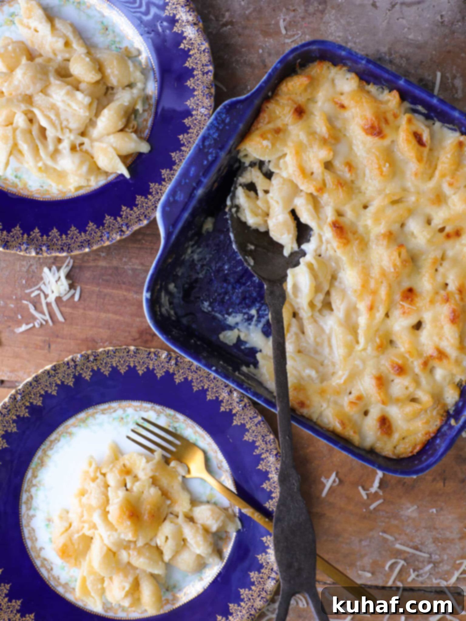 Two plates of white cheddar mac and cheese next to a blue baking dish full of the rest.