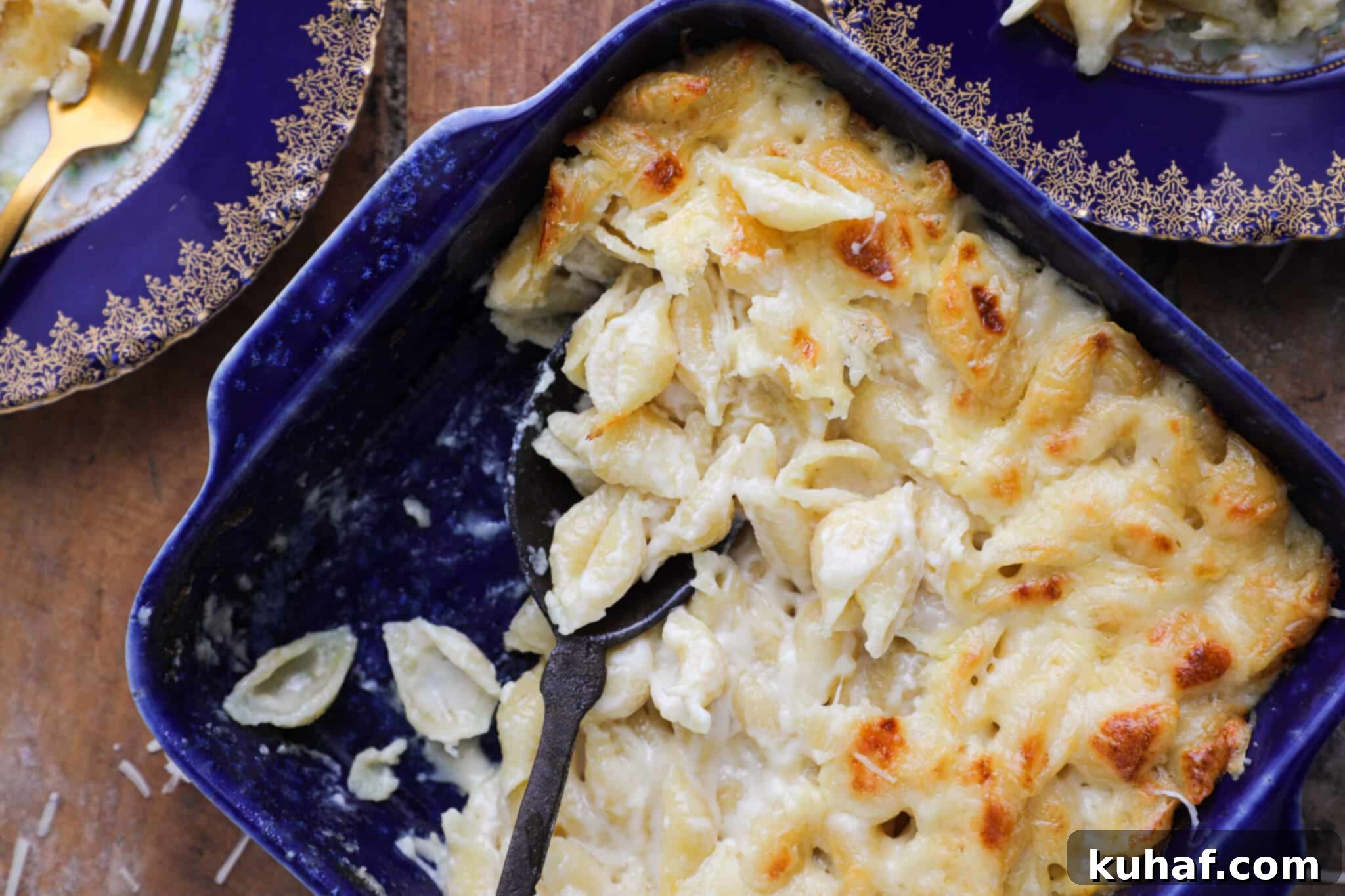 An almost full baking dish of white mac and cheese on a wood slate counter.
