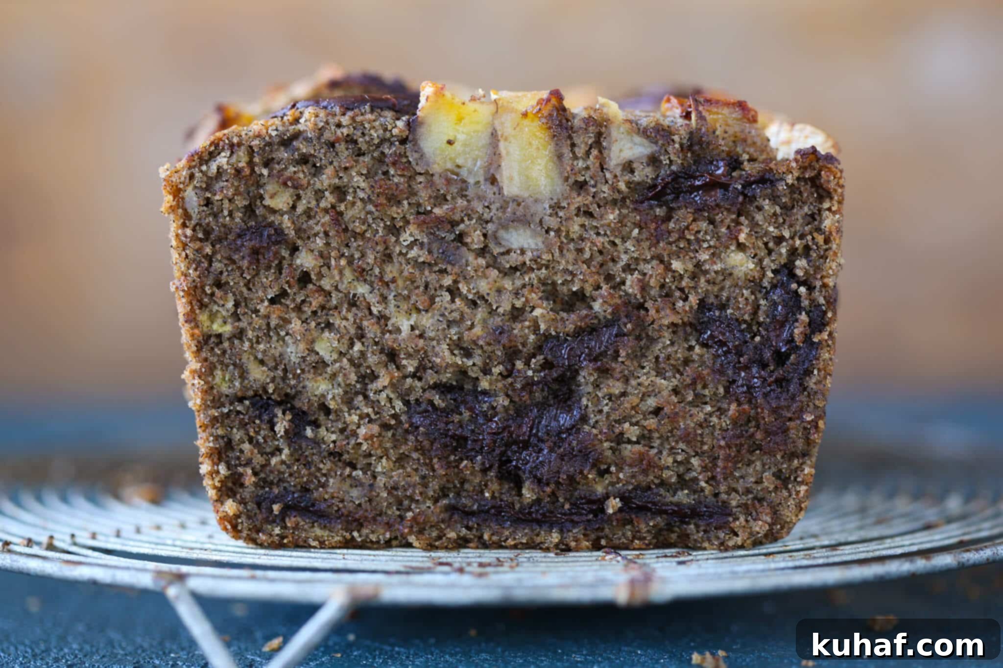 Side view of a loaf of vegan chocolate chip banana bread, showing its rustic texture and delightful height