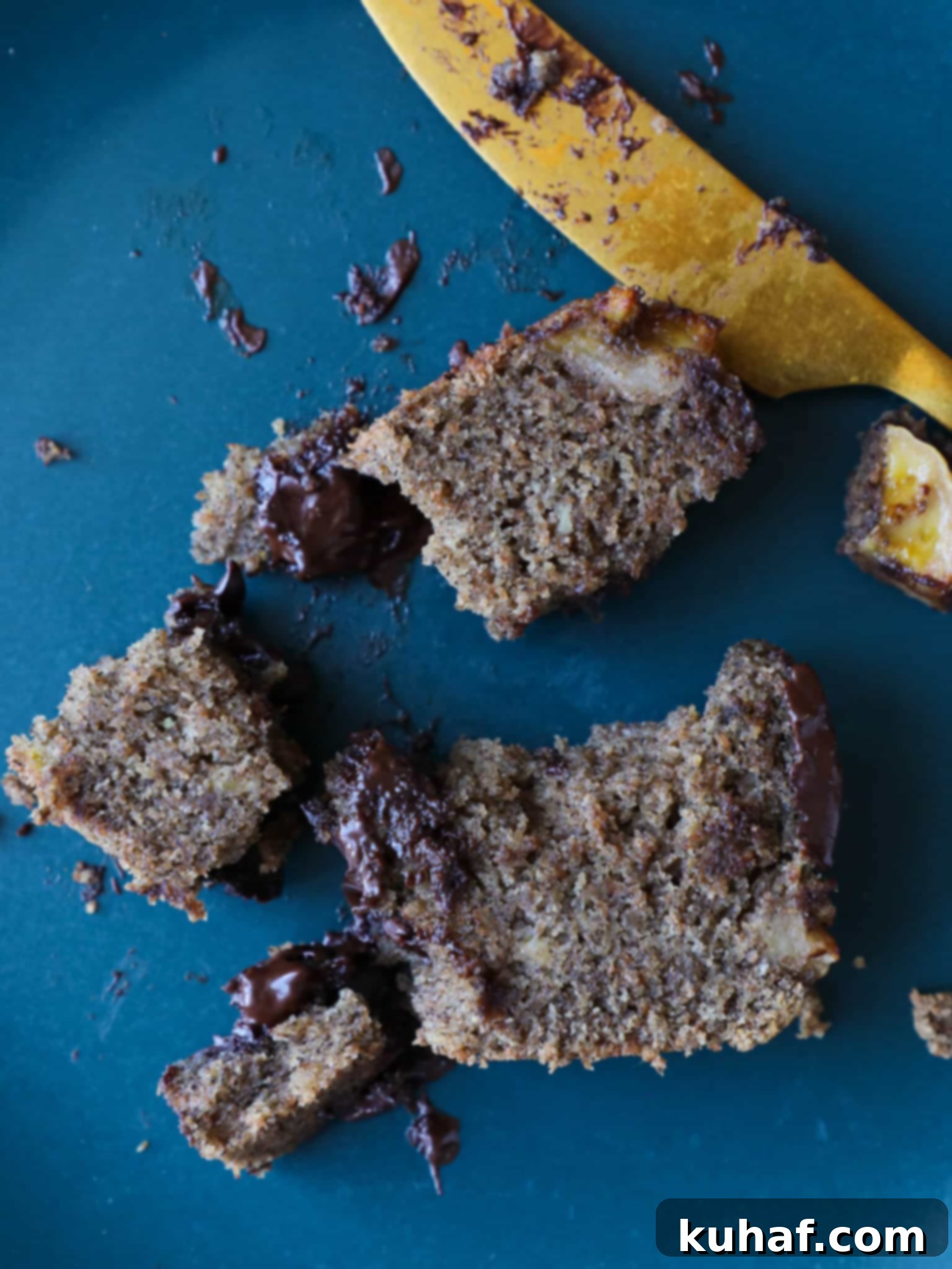 Hand reaching for a slice of vegan chocolate chip banana bread, emphasizing its deliciousness