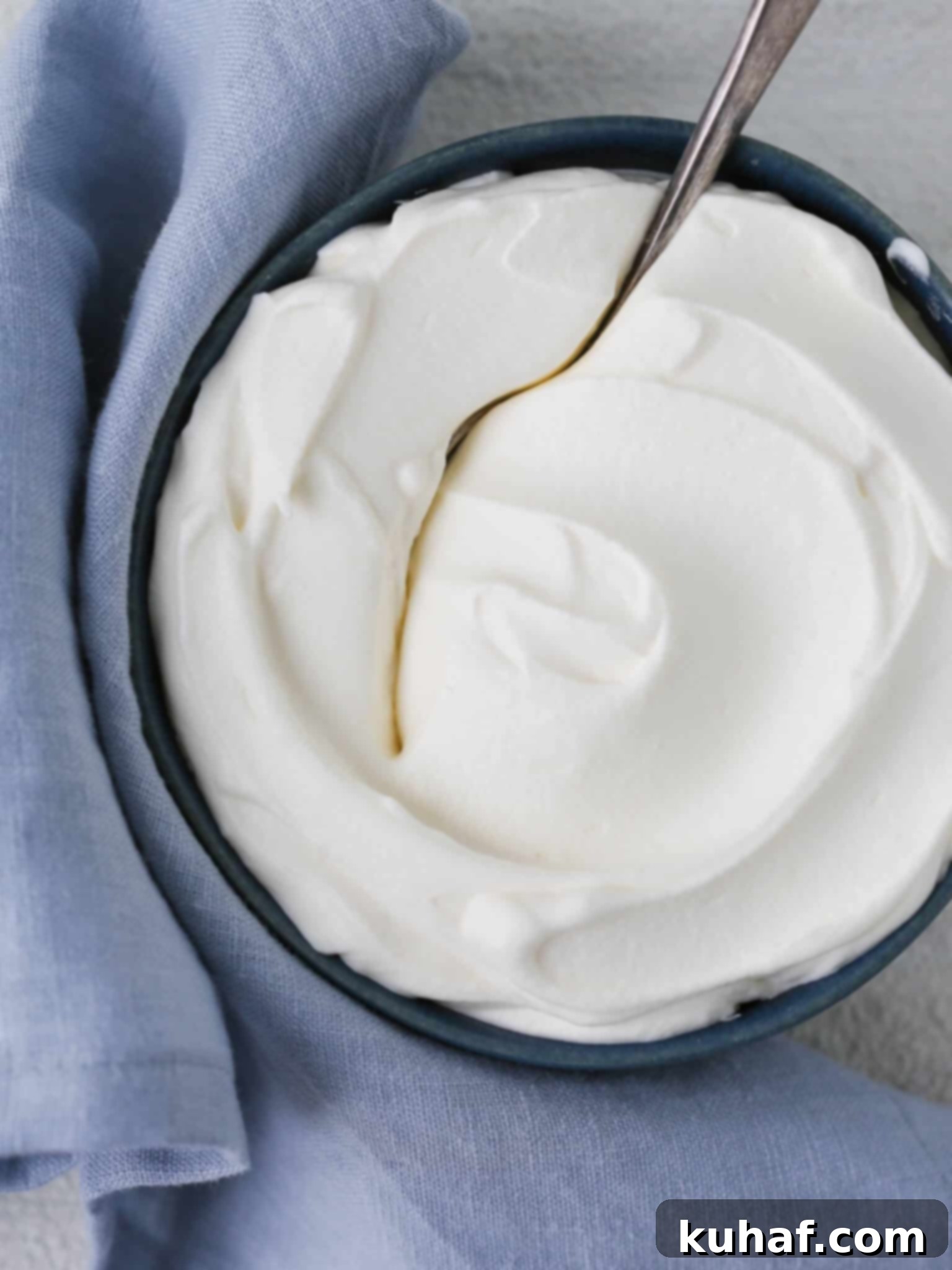 Homemade whipped cream in a rustic bowl with a blue napkin, ready to be served on a dessert.