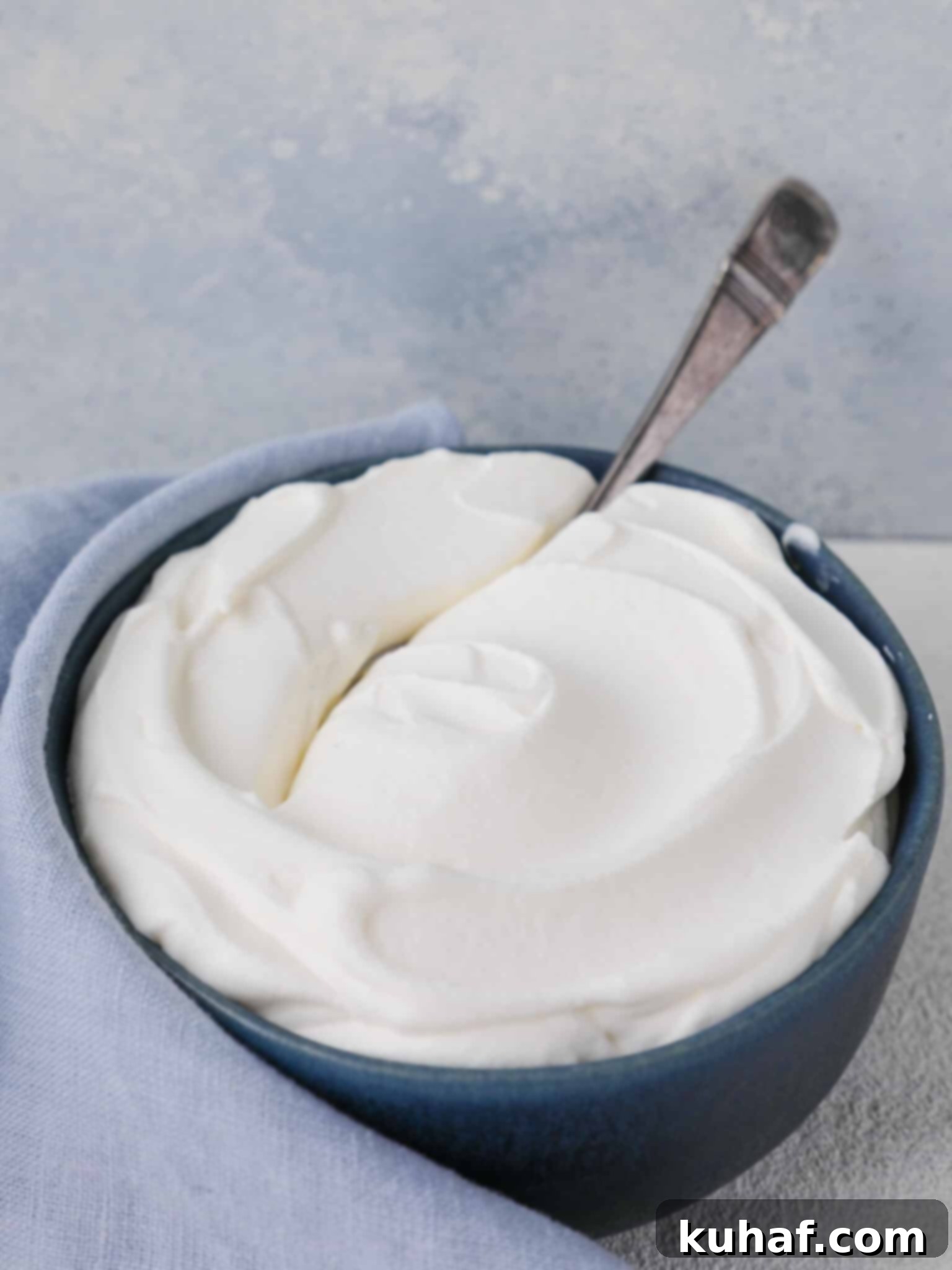Homemade whipped cream styled in elegant swirls on a vibrant blue background, ready for dessert plating.