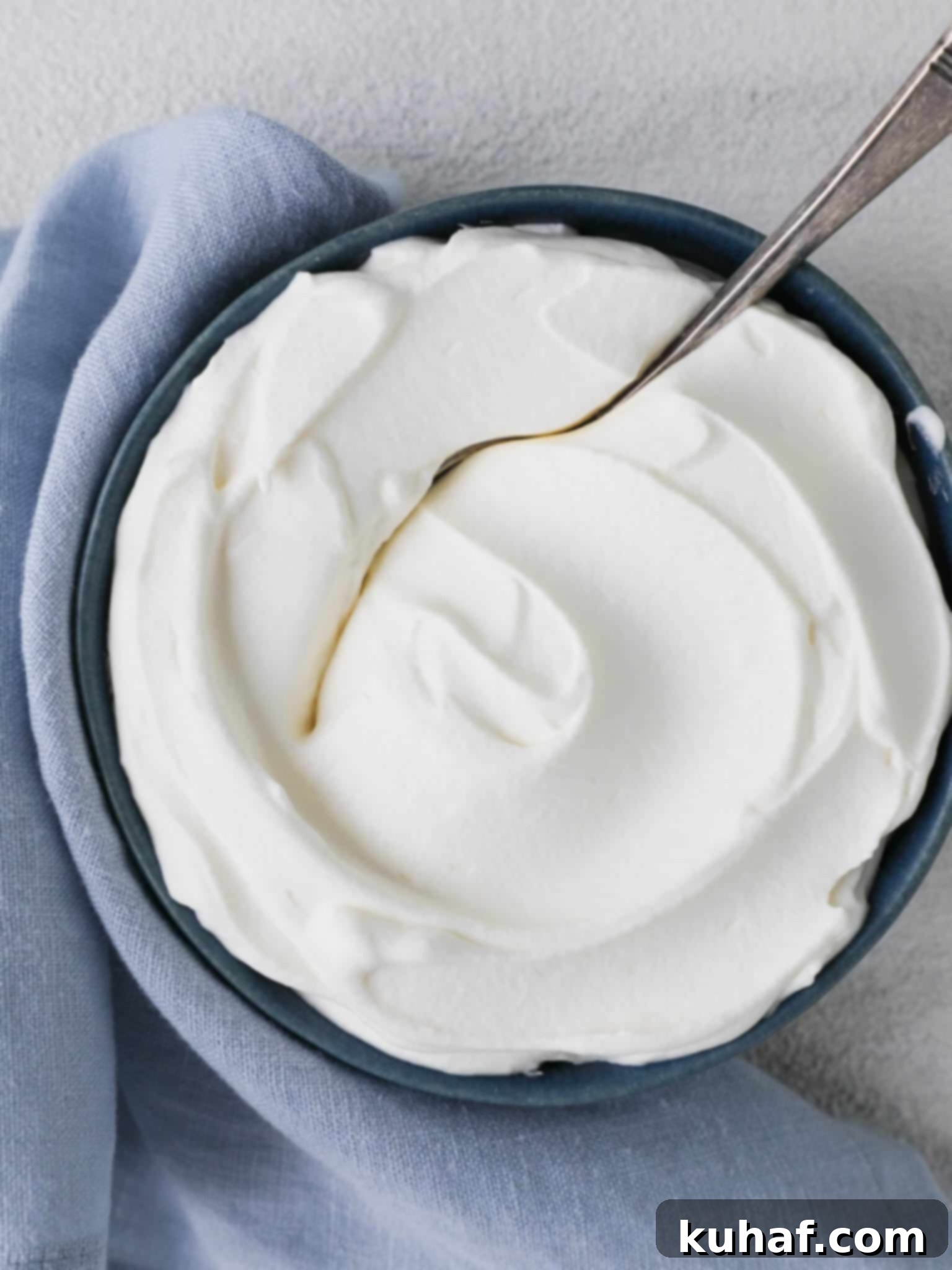 Homemade whipped cream served elegantly on a vintage spoon, emphasizing its rich and creamy texture.
