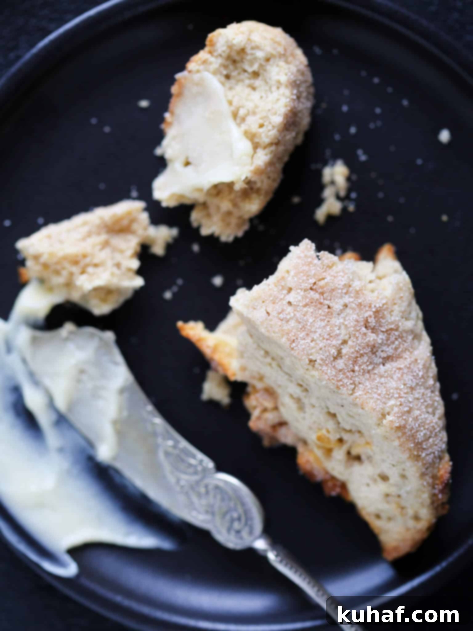 Warm Spiced Apple Scones 5 A spiced apple scone cut in half, revealing its tender interior and dried apple pieces, with a silver knife.