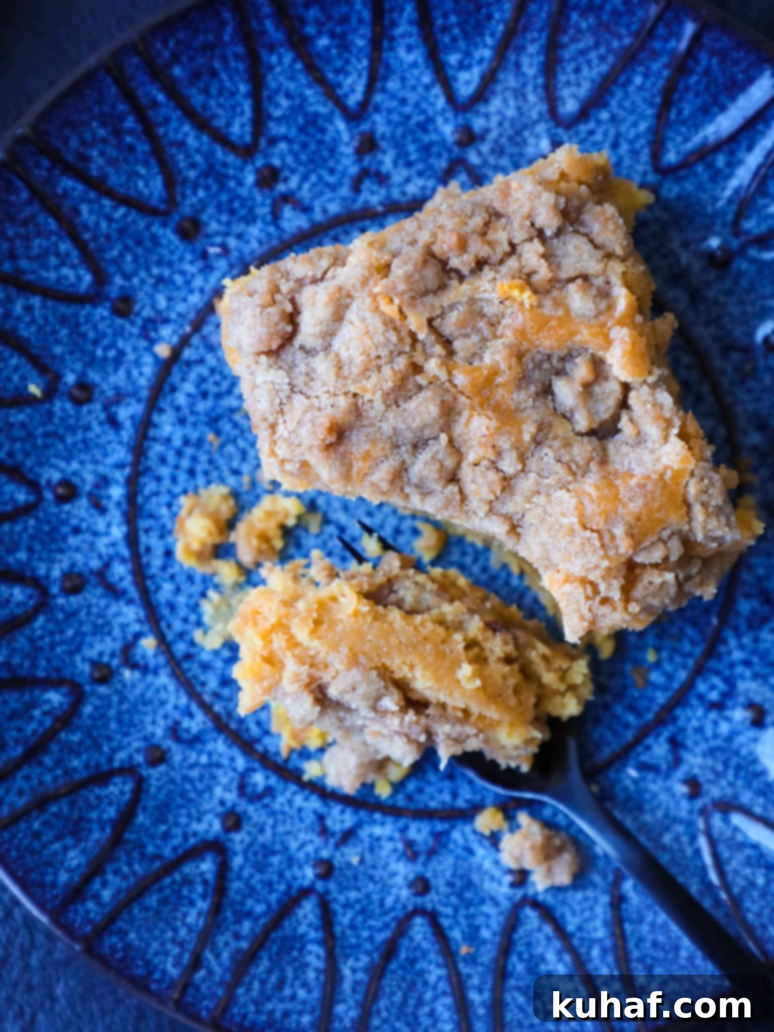 A perfectly sliced piece of pumpkin coffee cake on a bright blue plate, showing its moist texture and generous streusel topping.