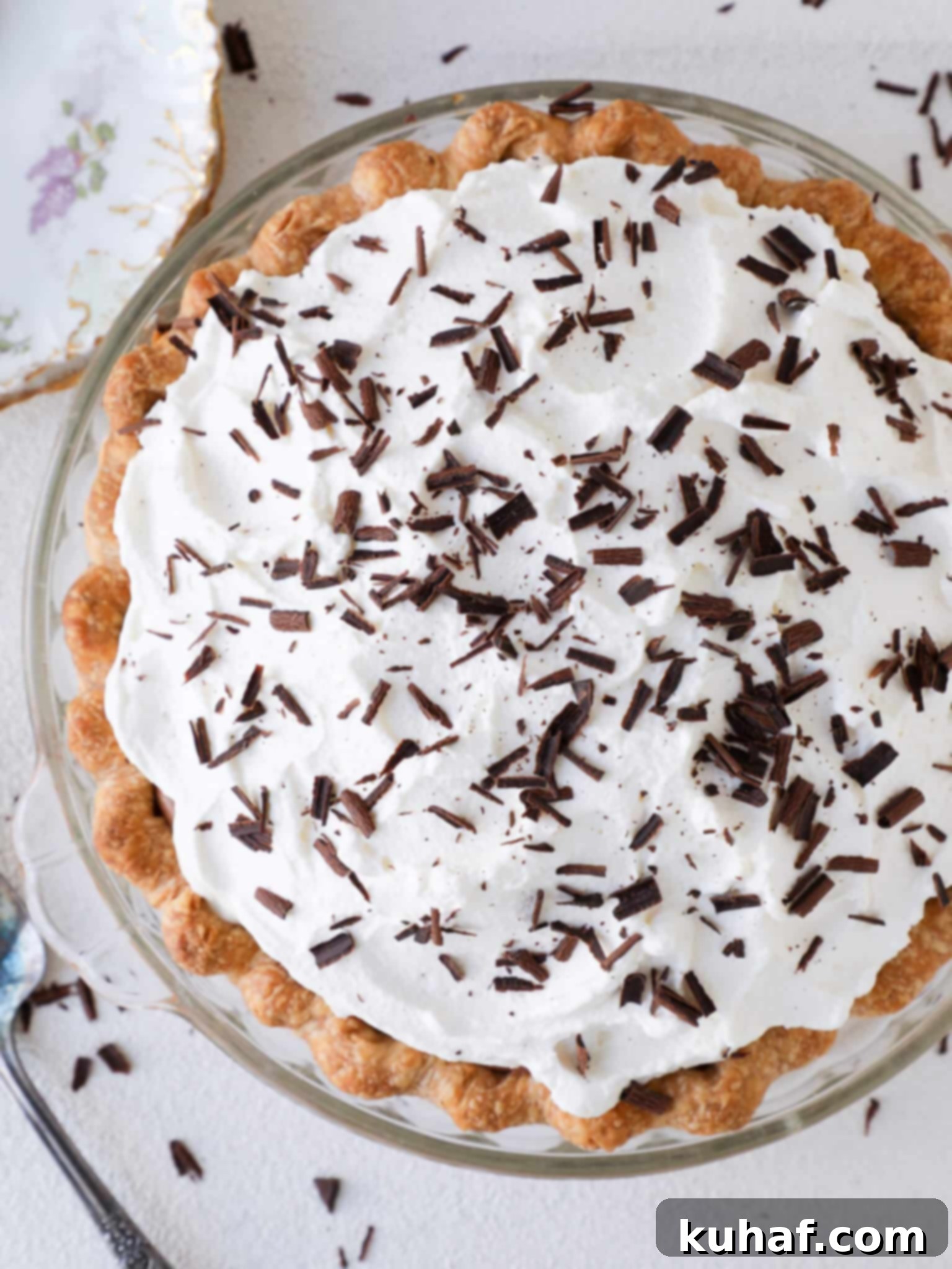 Overhead view of a whole French Silk Pie, adorned with elegant whipped cream swirls and chocolate shavings, presented in a rustic pie dish.
