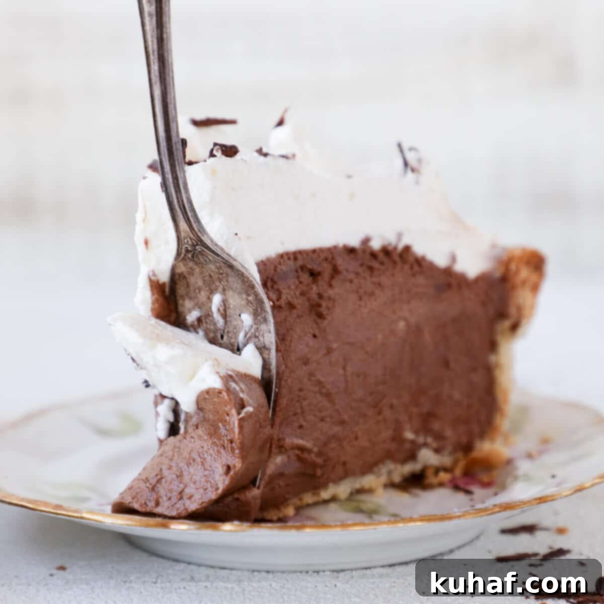 A slice of French Silk Pie on a white plate with a silver fork resting beside it, highlighting the smooth texture of the mousse and the crisp crust.