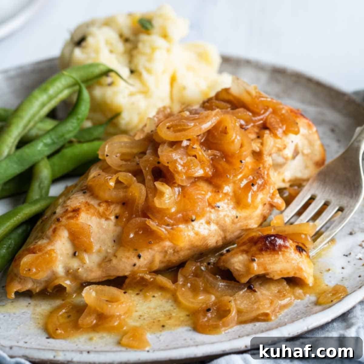 Chicken with shallots on a plate with a silver fork.