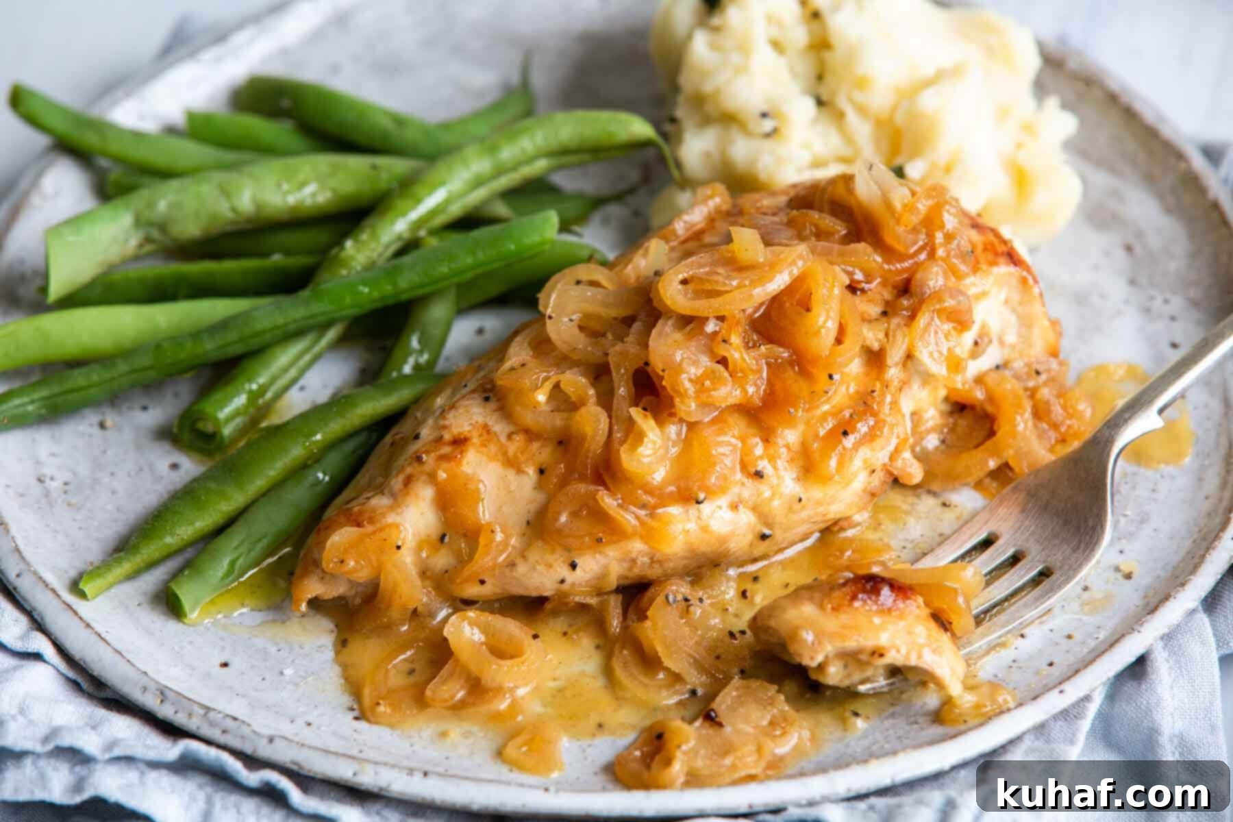 A serving of chicken with shallots on a beige plate.