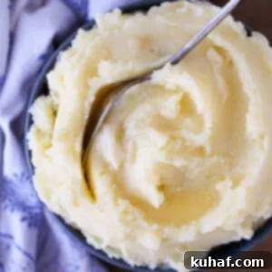 Creamy Mashed Potatoes Recipe served in a blue bowl with a vintage spoon.